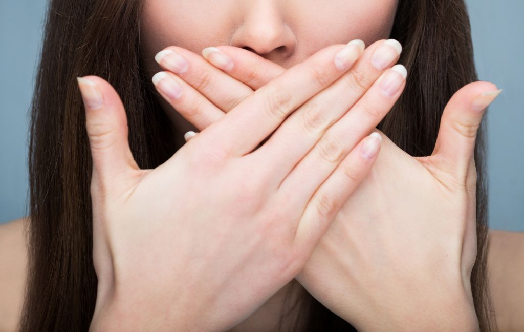 A woman covering her mouth in embarrassment due to a severe teeth condition.