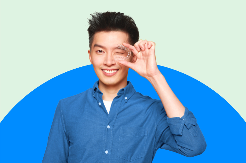 Man holding clear aligners and smiling