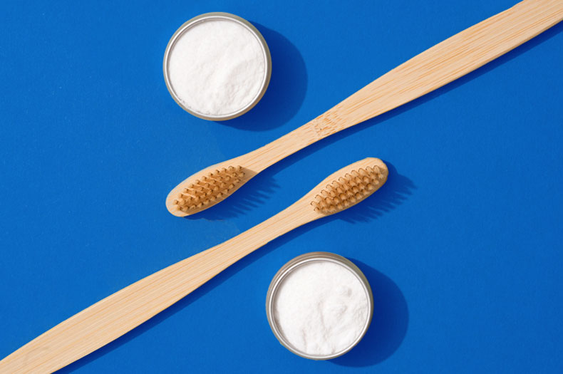 Two wooden toothbrushes in between two containers of toothpaste