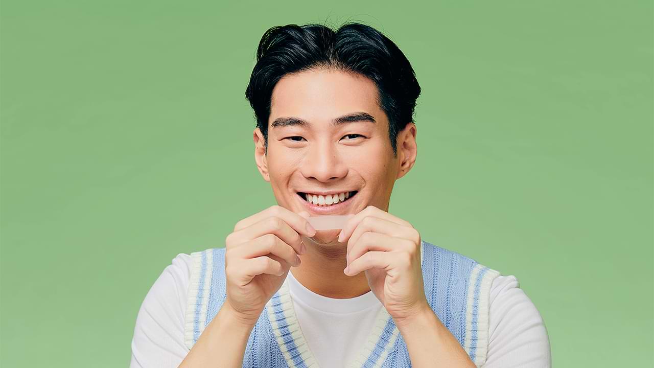 A guy holding whitening strips