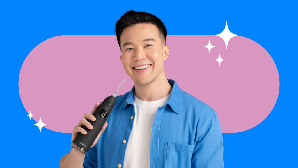 A male person smiling while holding the Zenyum Waterflosser Pro