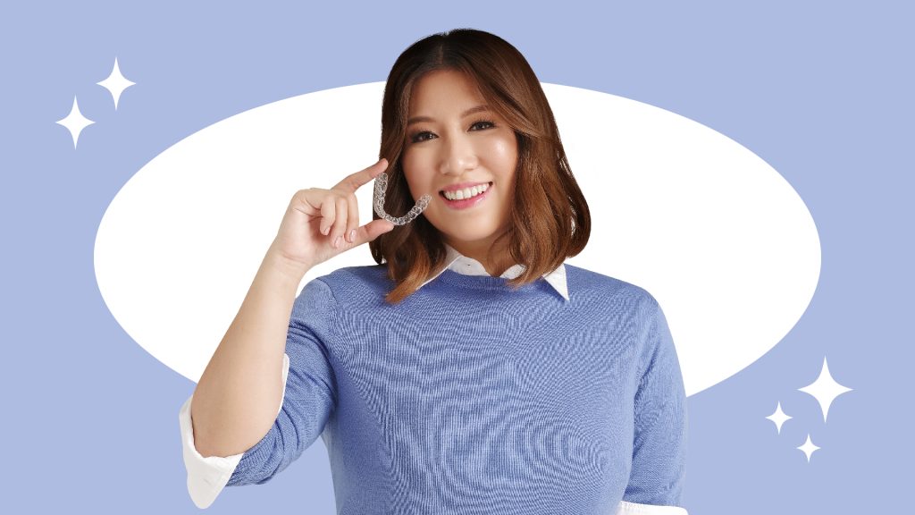 Women in blue smiling while holding a clear aligner