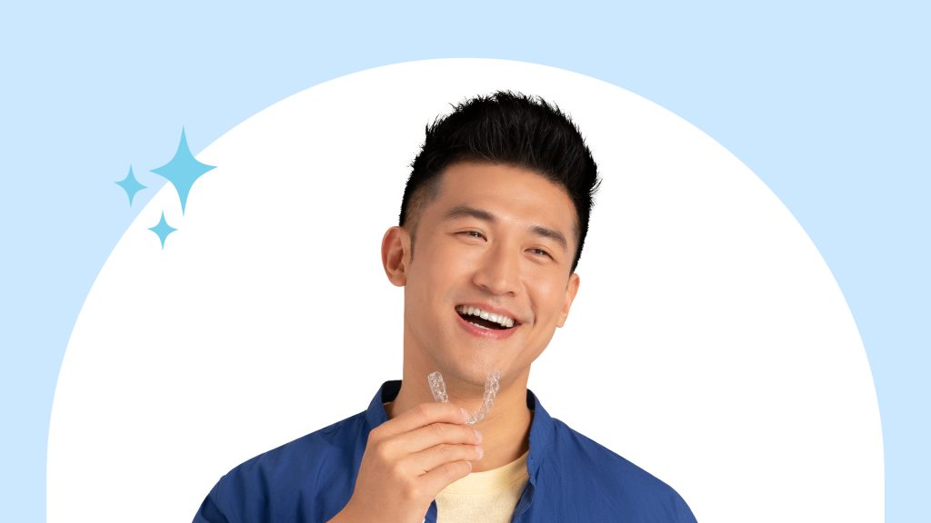 Man smiling and holding a set of aligners