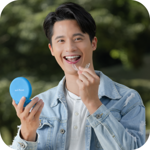 Guy smiling while holding Zenyum Invisible Braces